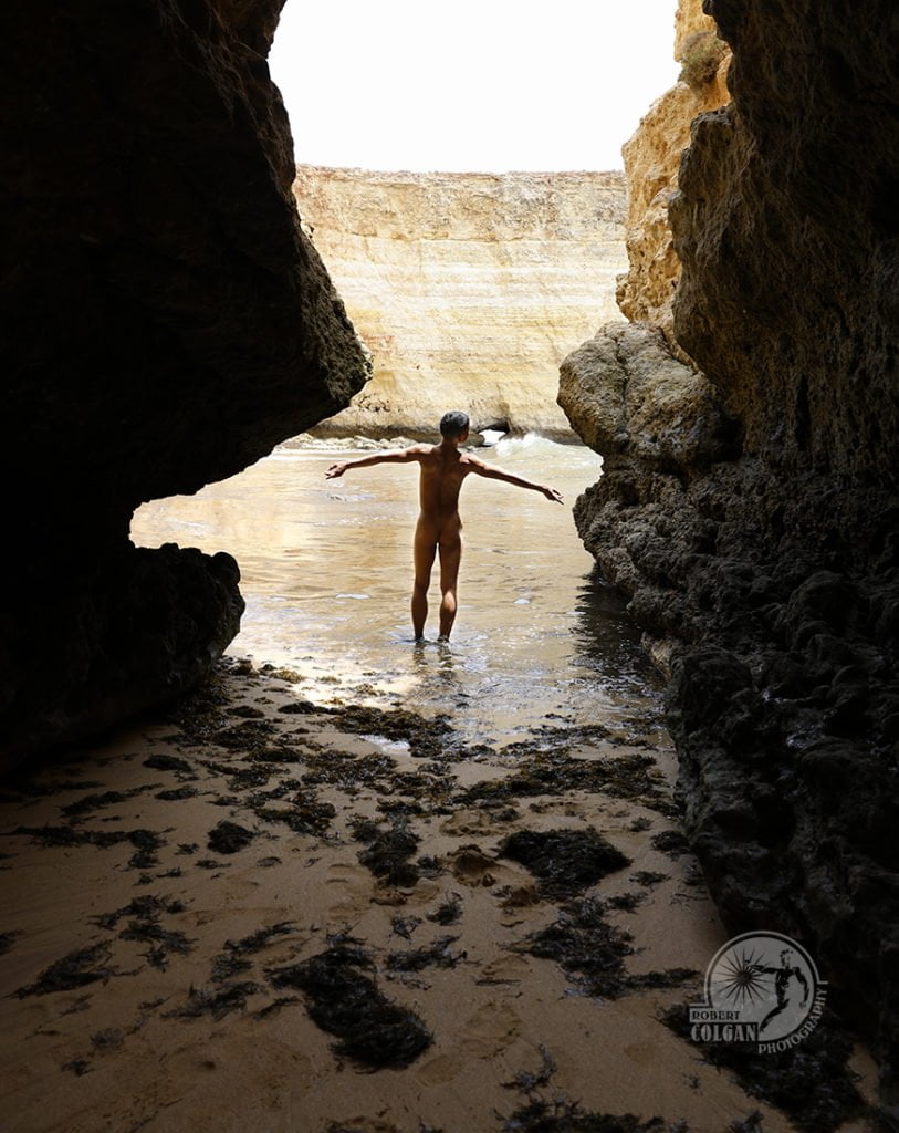 nude man greeting the ocean from a cave