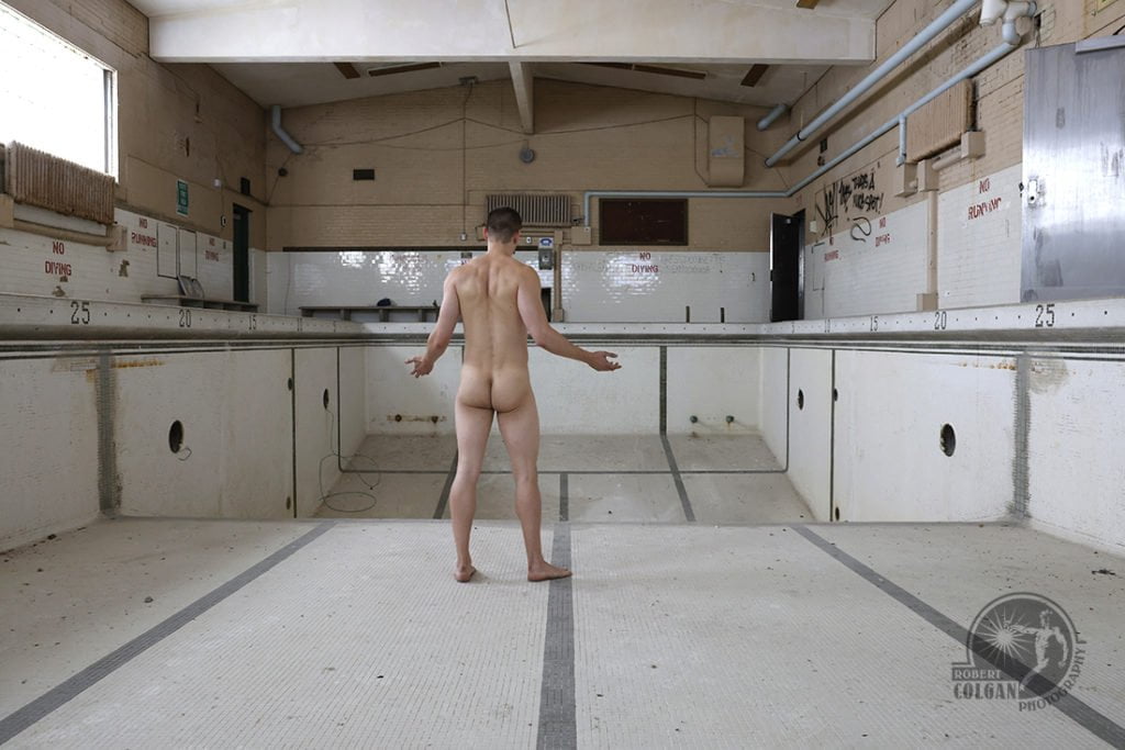 nude man stands in empty indoor swimming pool