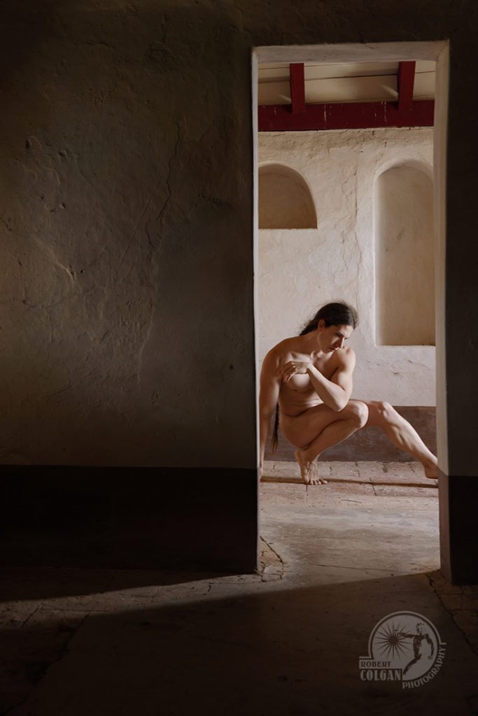 nude man, crouching low in doorway