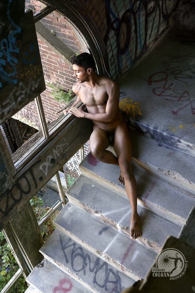looking down on nude man on stairs in old factory