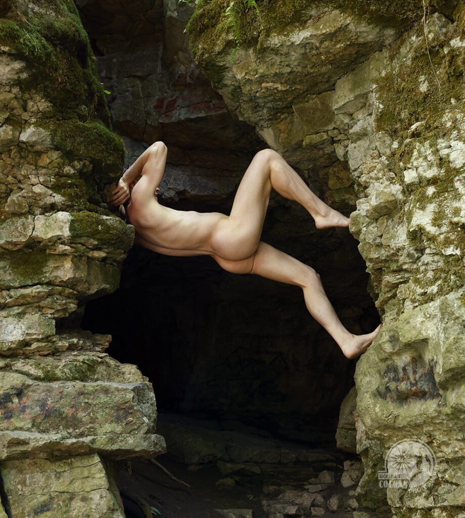 nude man stretches across cave opening
