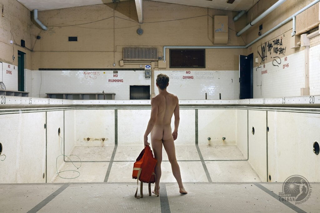 nude man stands in empty pool with life preserver