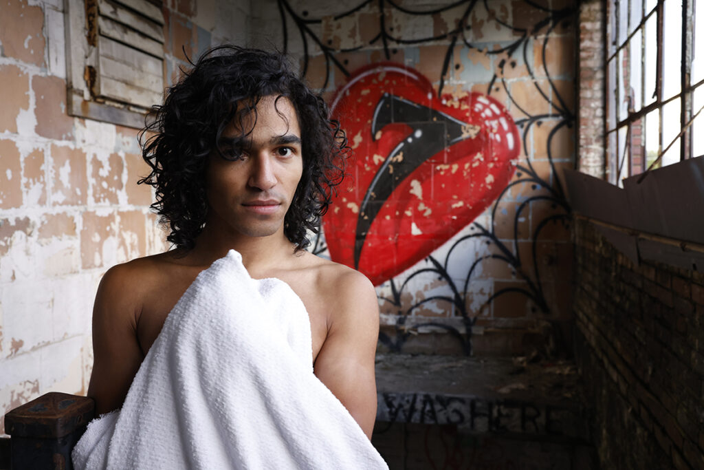 Shirtless man looks at viewer in abandoned building