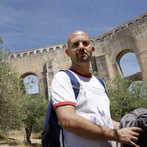 man looking at camera with aqueduct in background