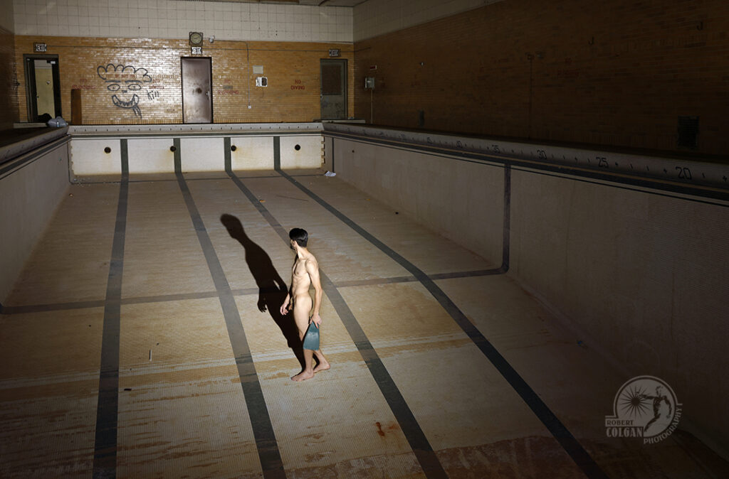nude man with swim fin in empty school pool