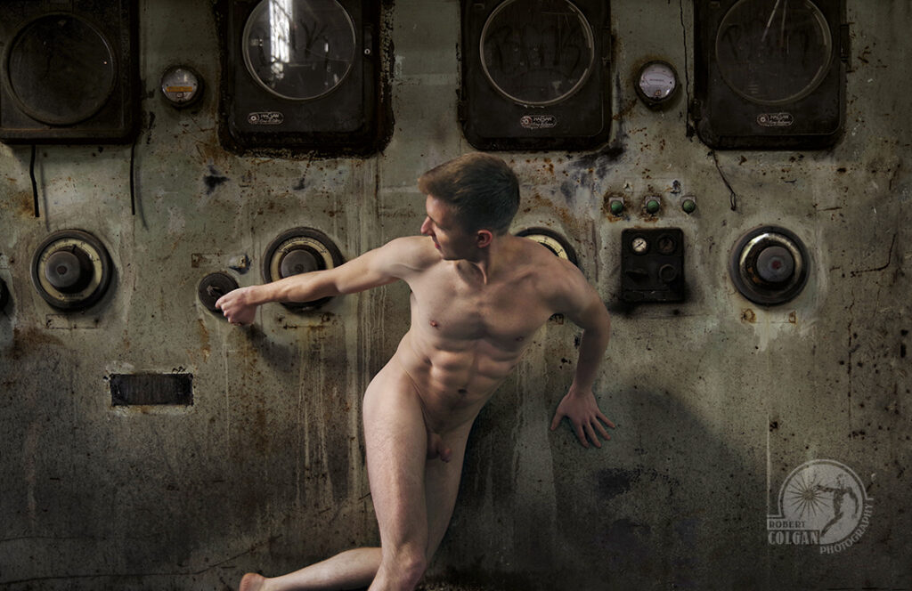 nude man pulls at controls in old factory