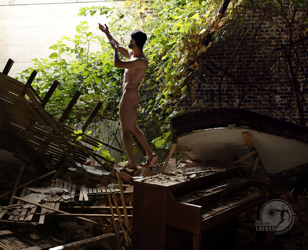 nude man gestures toward light in demolished wall