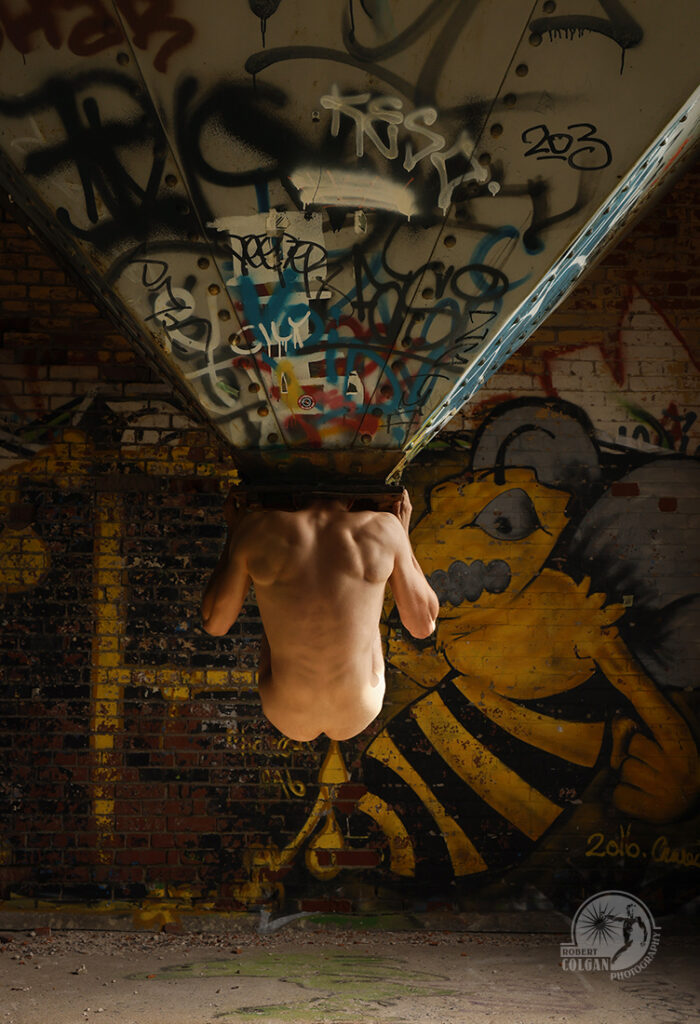 nude man grips giant funnel placing his head in the bottom opening