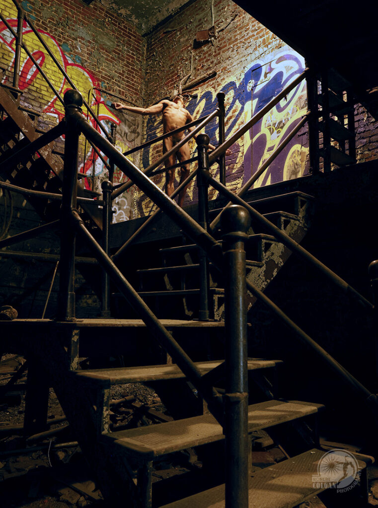 nude man posing near top of metal stairs