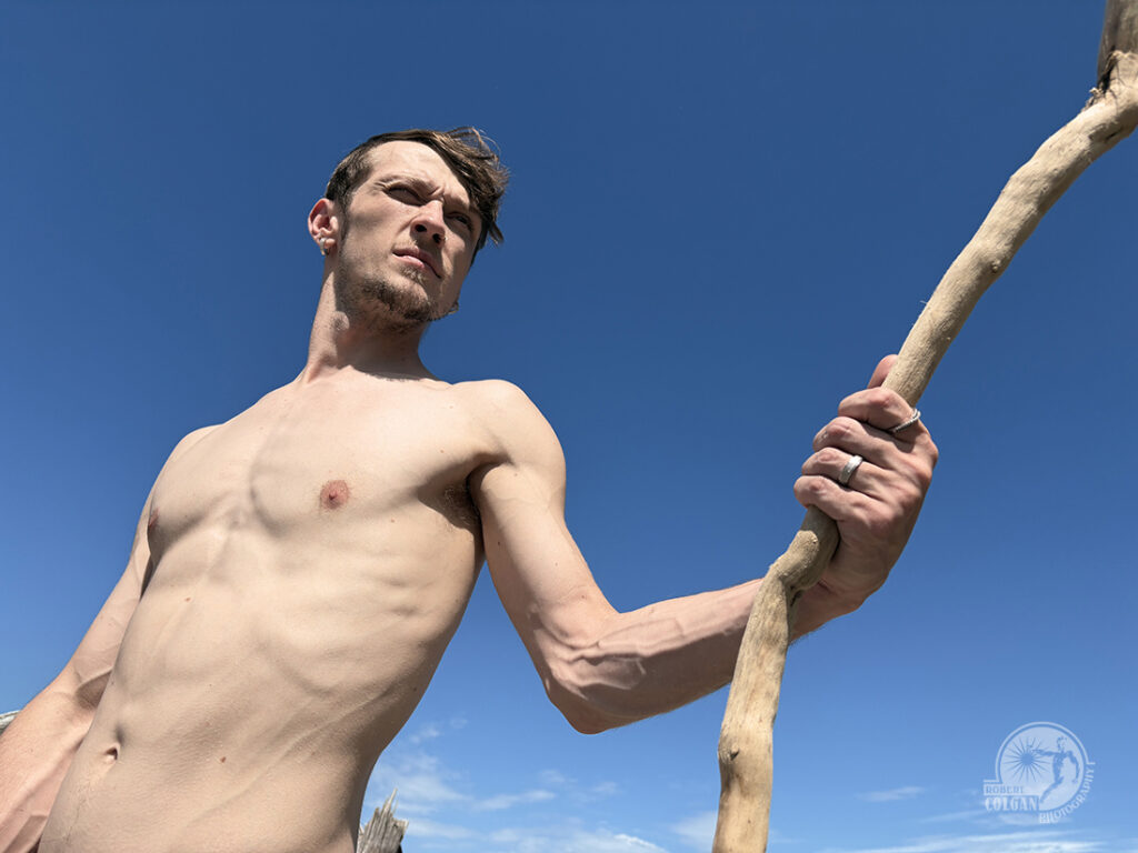 closeup of shirtless man holding stick