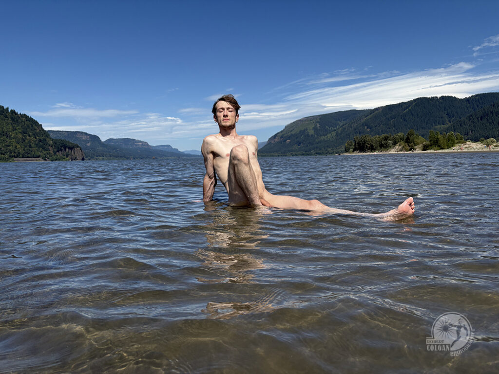 nude man sits in river soaking up the sun