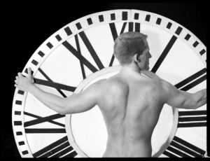 shirtless man embraces huge clock face in monochrome