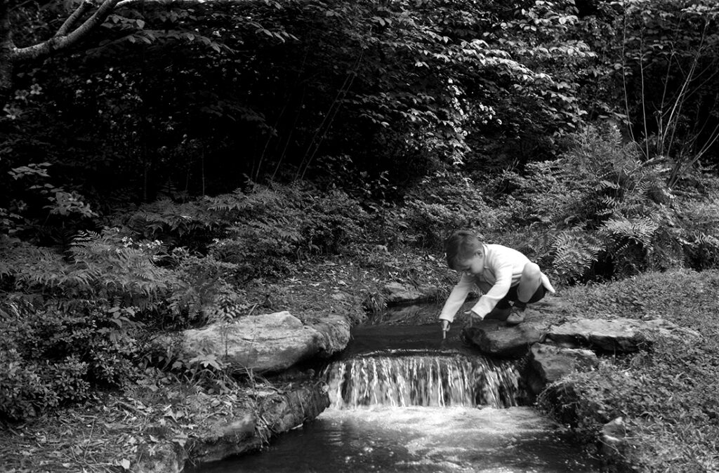 image of photographer as a child putting finger in waterfall