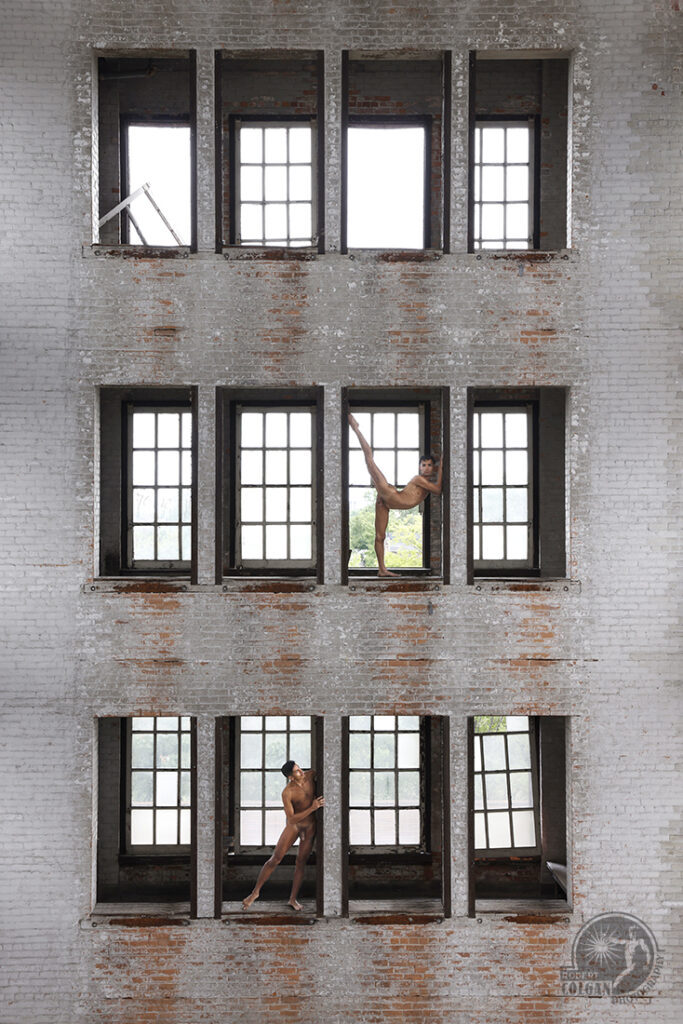two nude men perched in window openings of old fire training building