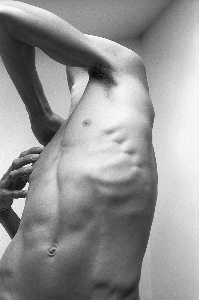 monochrome nude male shot from below with twisted torso