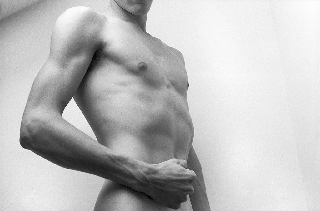 monochrome nude photographed from the side with flexed bicep