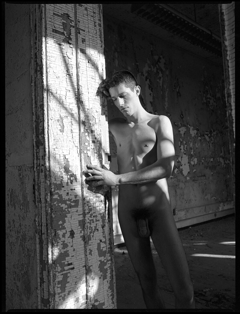 nude man in sun beams in old abandoned building