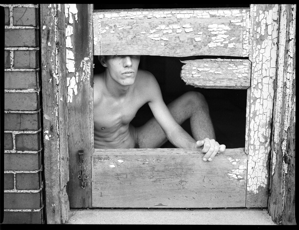 nude man peers out of broken door