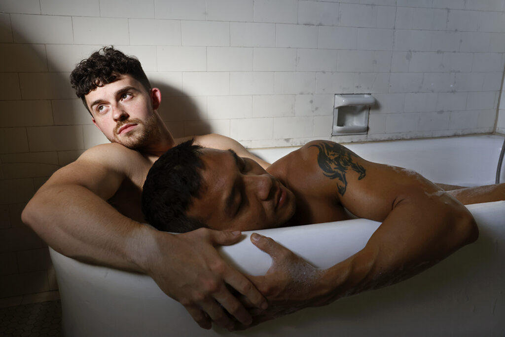 Two men in a tub, one looks back into a beam of light